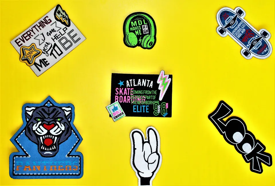 Colourful woven patches with tiger, headphones, skateboard and rock hand designs on a yellow background